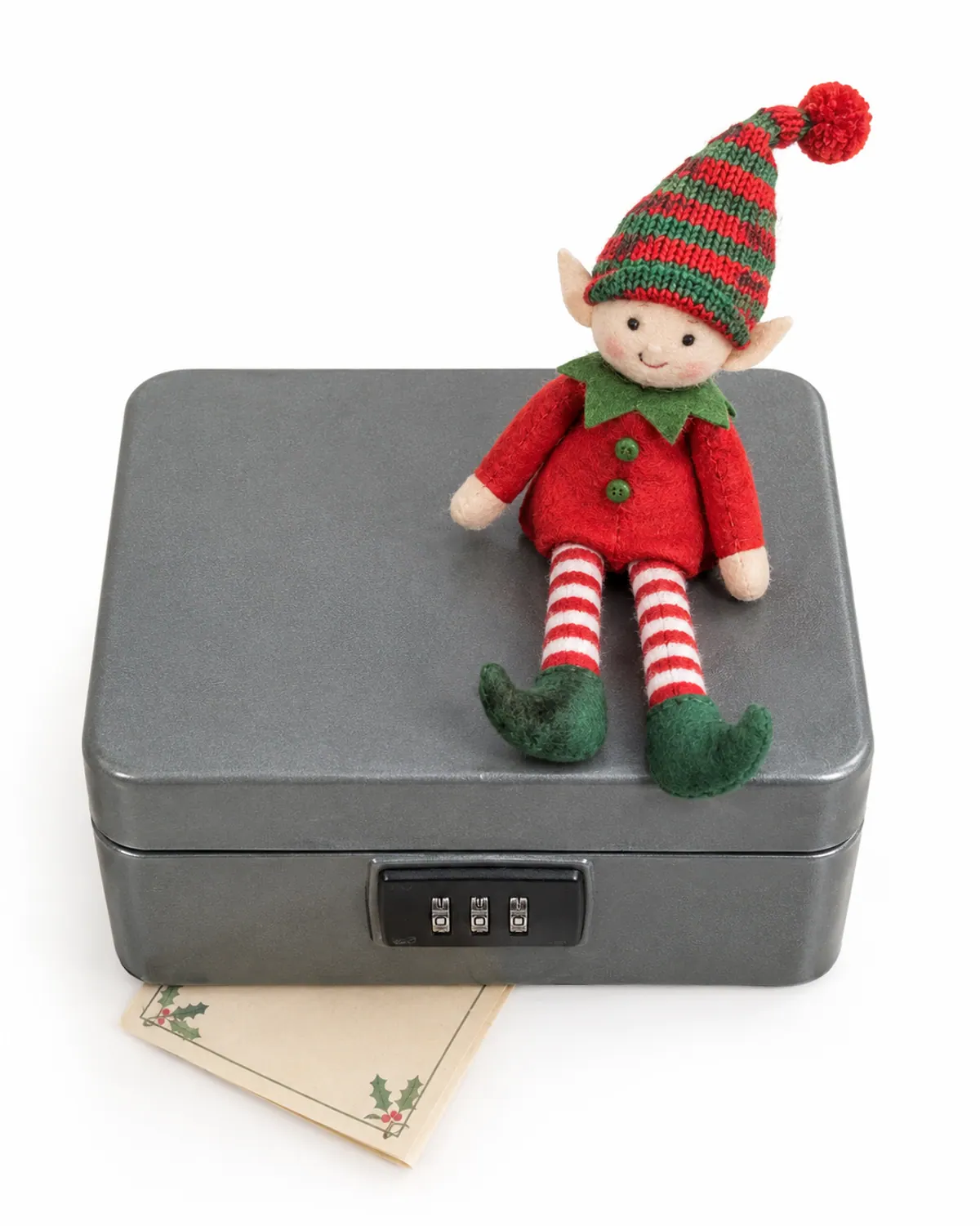 A small combination lockbox on a bookshelf with a felt elf doll sitting on top and a clue card tucked underneath