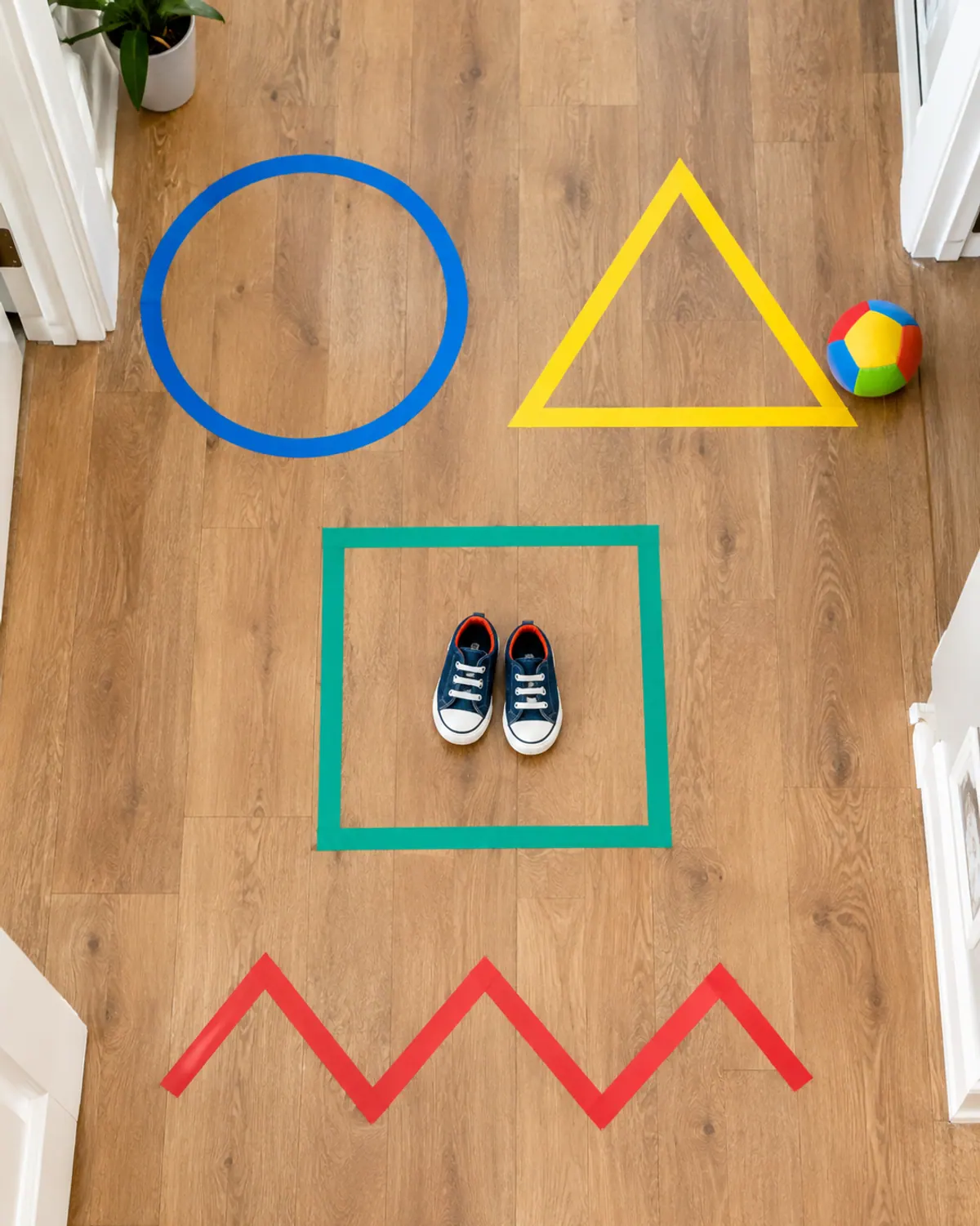 Painter's tape circle, square, triangle and zigzag on a hallway floor with small toddler sneakers standing in the square